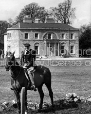 Actor/Director John Huston, sitting on top of his horse in front of his large home.