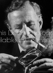 British mystery writer Ian Fleming looking at pirate coins through a magnifying glass.