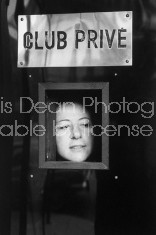 Regine, owner of chic clubs in Paris and on the Riviera, peering through door at a would-be patron.