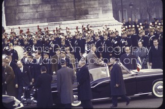 French President Charles de Gaulle standing in an open car driving up the Champs Elysees to the Arc de Triomphe ceremony on his Inauguration day.